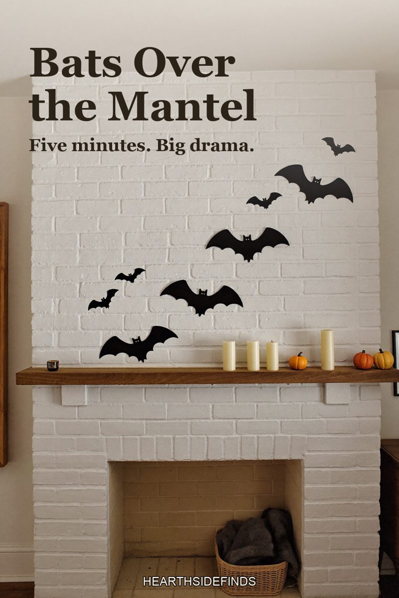 White brick fireplace with pumpkins and candles on the mantel and black paper bats swirling up the wall above.