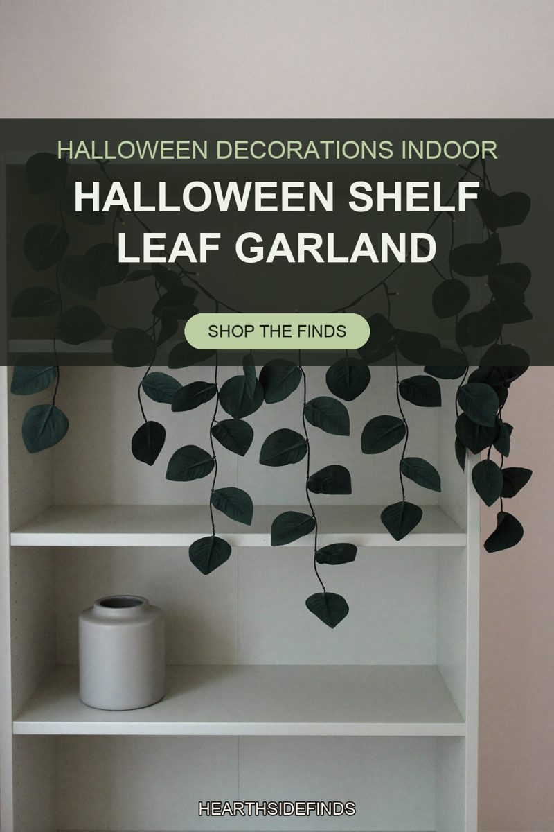 Dark green faux leaf garland with fairy lights draped on a white bookcase above a small gray ceramic vase.