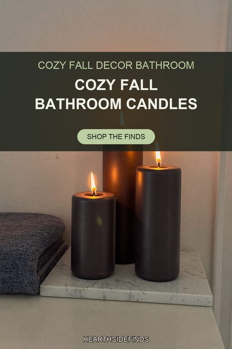 Three matte black pillar candles burning on a white marble tray beside folded blue-gray towels.