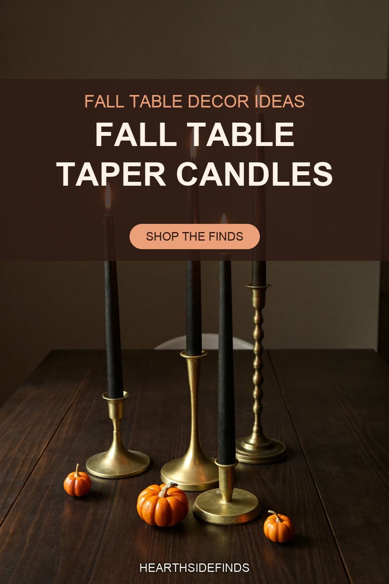 Four black taper candles in mismatched brass holders on a dark wood table with three orange mini pumpkins.