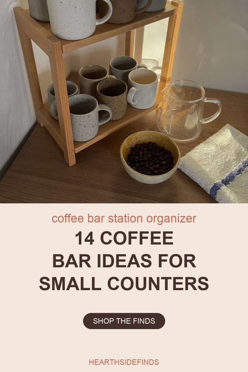 Photo of a two-tier wooden shelf riser on a dark wood counter holding six speckled stoneware mugs on its lower shelf, one of them filled with a pale drink, and four more mugs on the upper shelf whose tops are cut off by the top edge of the frame, with a clear glass jug, a small stoneware bowl of whole roasted coffee beans and a folded cream towel with a navy stripe on the counter beside it