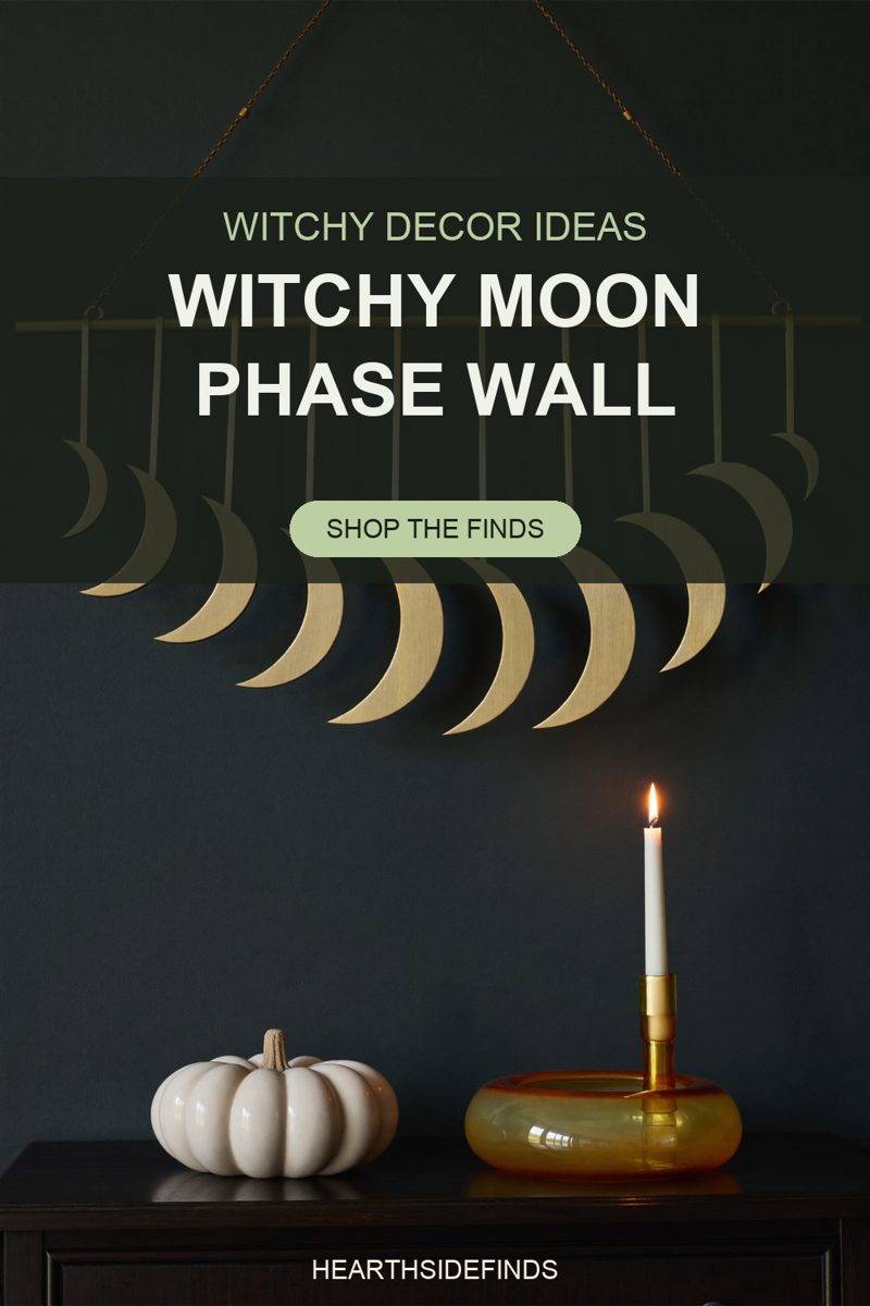 Brass moon phase wall hanging on a dark green wall above a cream ceramic pumpkin and amber glass holder.