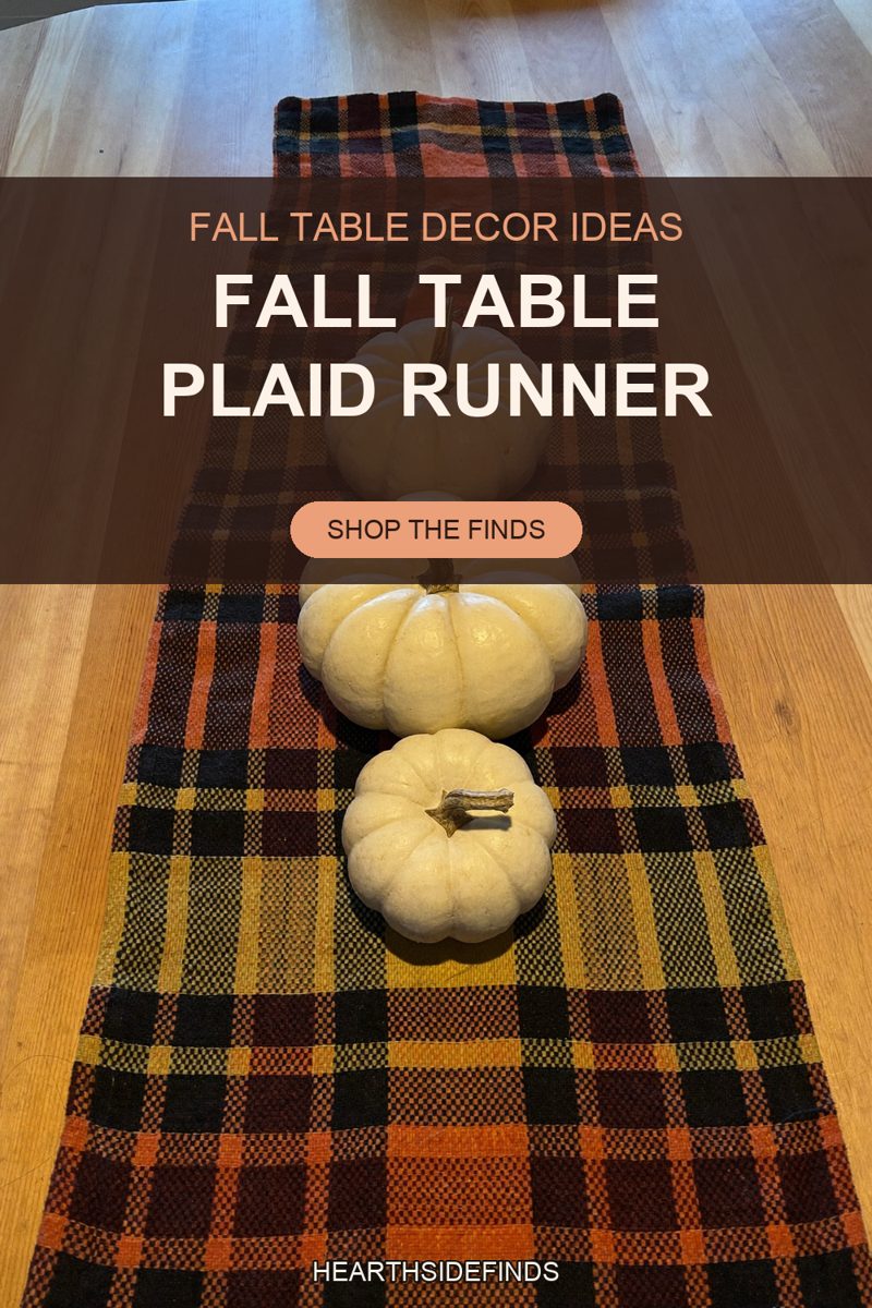 Orange, mustard and black plaid runner down a light wood table with three cream mini pumpkins in a row.